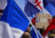 No Vaccine? No Cafe, According to New French Virus Law FILE - A protestor waves a sign which reads 'freedom' in the middle of French flags during a demonstration in Paris, France, Saturday, July 31, 2021. Photo: Michel Euler / AP File
