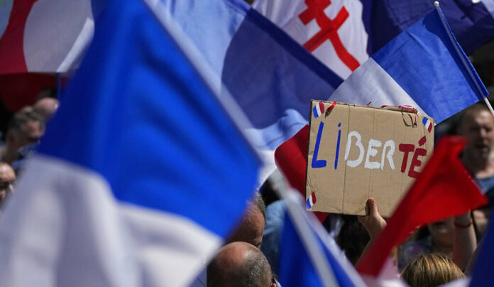 FILE - A protestor waves a sign which reads 'freedom' in the middle of French flags during a demonstration in Paris, France, Saturday, July 31, 2021. Photo: Michel Euler / AP File