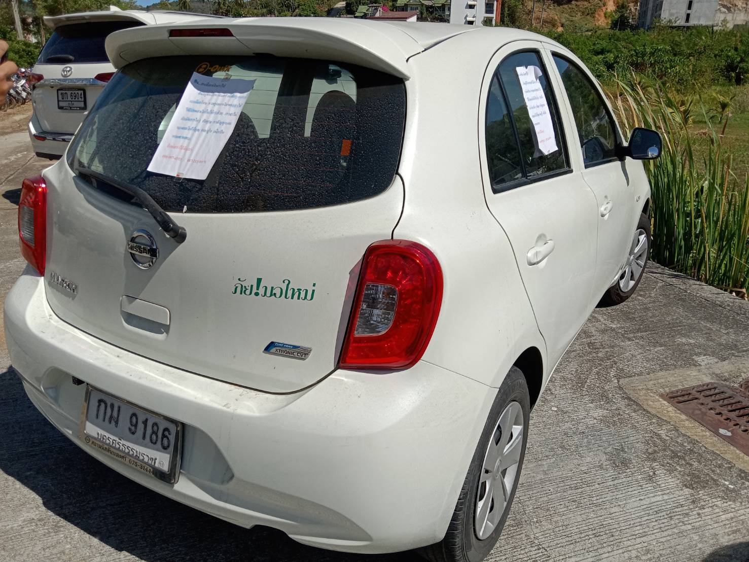 Alexandos's car, with a sign in Thai pledging the return of his cash put up on the windows.