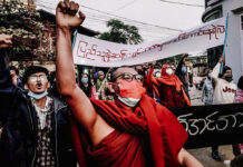 Violence, Protests Mark Anniversary of Myanmar Army Rule A Buddhist monk raises his clenched fist while marching during an anti-military government protest rally on Tuesday, Feb. 1, 2022, in Mandalay, Myanmar. Photo: AP