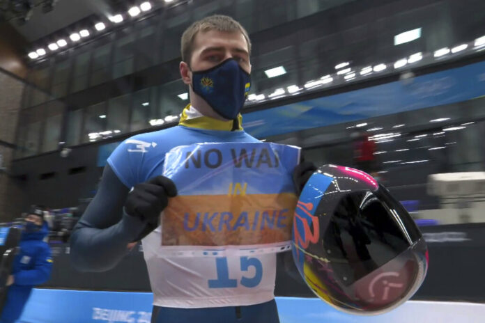 In this frame from video, Vladyslav Heraskevych, of Ukraine, holds a sign that reads 