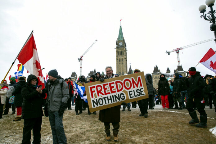 Don Stephens, 65, a retired graphic designer, holds a sign on Parliament Hill to support trucks lined up in protest of COVID-19 vaccine mandates and restrictions in Ottawa, Ontario, on Saturday, Feb. 12, 2022. Photo: Ted Shaffrey / AP