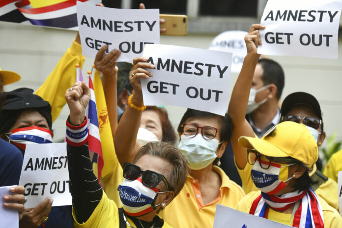 Thai royalists protesters hold a sign against Amnesty International Thailand during the protest in Bangkok, Thailand, Thursday, Nov. 25, 2021. Photo: Panumas Sanguanwong / AP