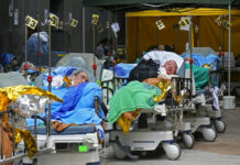 Hong Kong Hospitals Hit 90% Capacity as COVID-19 Cases Surge Patients lie on hospital beds as they wait at a temporary holding area outside Caritas Medical Centre in Hong Kong Wednesday, Feb. 16, 2022. Photo: Vincent Yu / AP