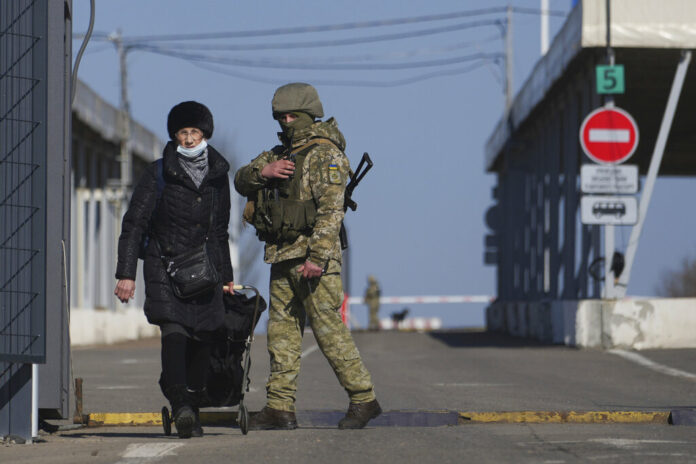 A woman crosses a checkpoint from the territory controlled by Russia-backed separatists to the territory controlled by Ukrainian forces in Novotroitske, eastern Ukraine, Monday, Feb. 21, 2022. Photo: Evgeniy Maloletka / AP