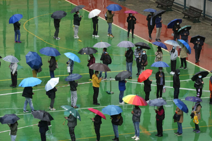 Residents line up to get tested for the coronavirus at a temporary testing center despite the rain in Hong Kong, Tuesday, Feb. 22, 2022. Photo: Kin Cheung / AP