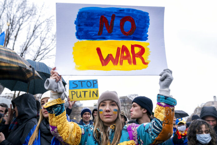 A tear rolls down through the colors of the Ukrainian flag on the cheek of Ukranian Oleksandra Yashan of Arlington, Va., as she becomes emotional while holding a sign that reads 