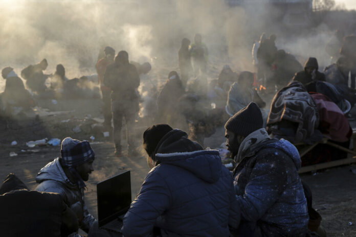 Refugees try to stay warm after fleeing the Russian invasion of Ukraine, at the Medyka border crossing in Poland, Tuesday, March 1, 2022. Photo: Visar Kryeziu / AP
