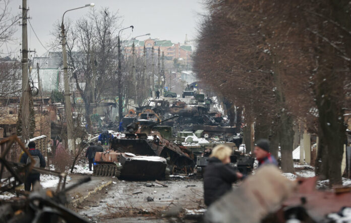 People look at the gutted remains of Russian military vehicles on a road in the town of Bucha, close to the capital Kyiv, Ukraine, Tuesday, March 1, 2022. Photo: Serhii Nuzhnenko / AP