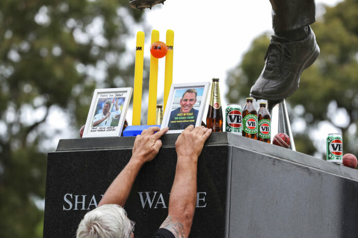A man places a set of cricket stumps and a photos at the statue of Shane Warne outside the Melbourne Cricket Ground in Melbourne, Australia, Saturday, March 5, 2022. Photo: Asanka Brendon Ratnayake / AP