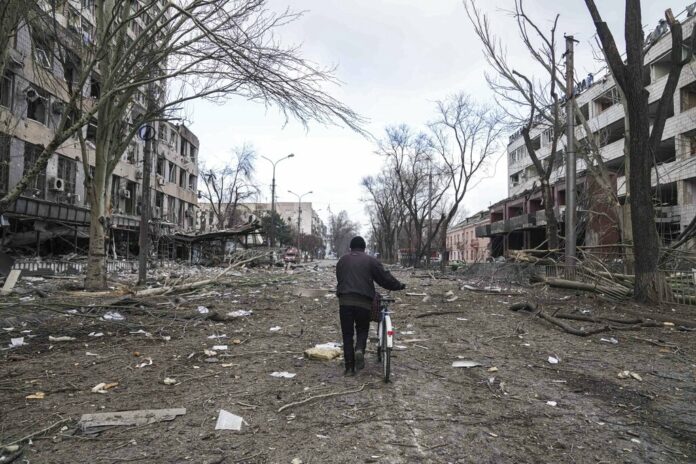 A man walks with a bicycle in a street damaged by shelling in Mariupol, Ukraine, Thursday, March 10, 2022. Photo: Evgeniy Maloletka / AP