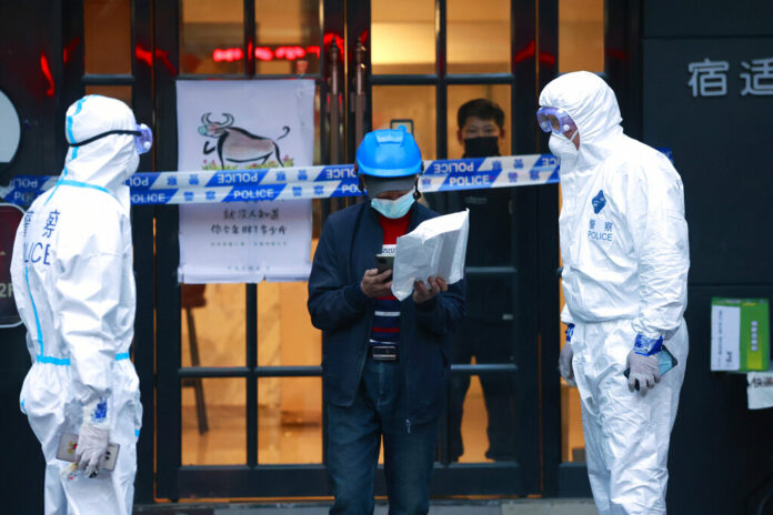 FILE - A delivery man walks by police officers with protective suit outside of a hotel in Shanghai, China, on March 15, 2022. Photo: AP FILE - A delivery man walks by police officers with protective suit outside of a hotel in Shanghai, China, on March 15, 2022. Photo: AP