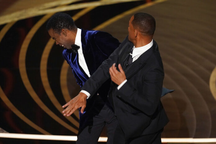 Will Smith, right, hits presenter Chris Rock on stage while presenting the award for best documentary feature at the Oscars on Sunday, March 27, 2022, at the Dolby Theatre in Los Angeles. Photo: Chris Pizzello / AP