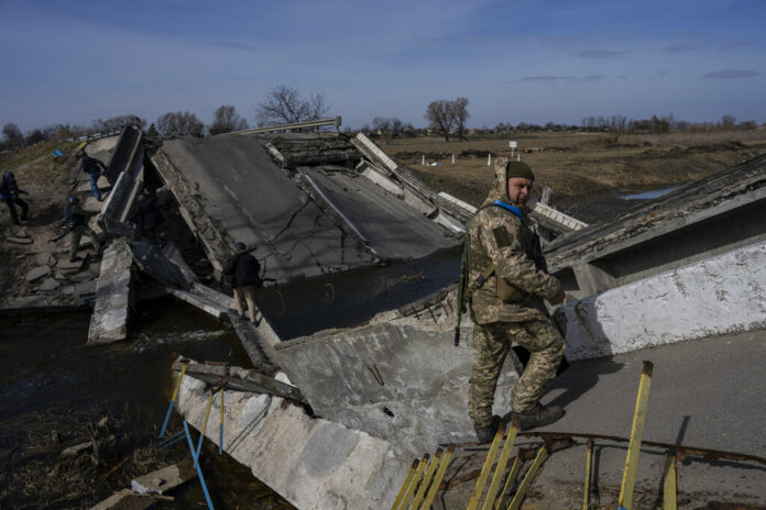 A soldier stands on a bridge destroyed by the Ukrainian army to prevent the passage of Russian tanks near Brovary, in the outskirts of Kyiv, Ukraine, Monday, March 28, 2022. Photo: Rodrigo Abd / AP
