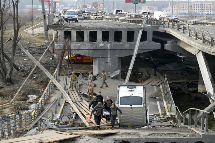 Ukrainian soldiers carry a body of a civilian killed by the Russian forces over the destroyed bridge in Irpin close to Kyiv, Ukraine, Thursday, March 31, 2022. Photo: Efrem Lukatsky / AP