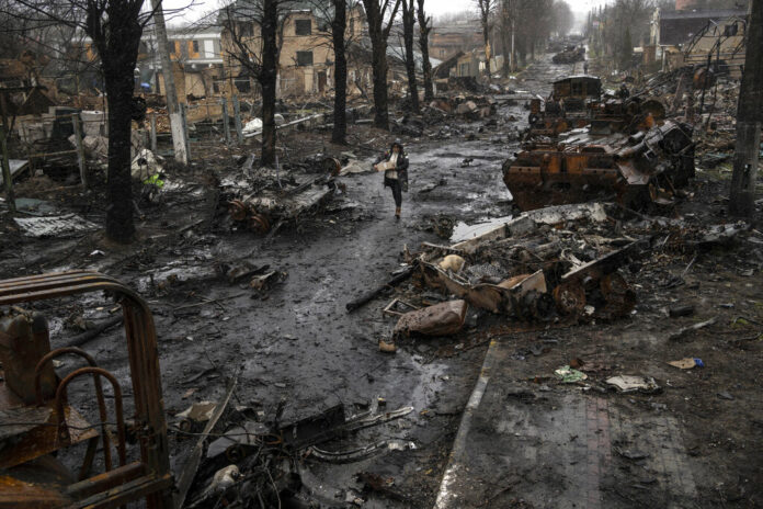 A woman walks amid destroyed Russian tanks in Bucha, in the outskirts of Kyiv, Ukraine, Sunday, April 3, 2022. Photo: Rodrigo Abd / AP