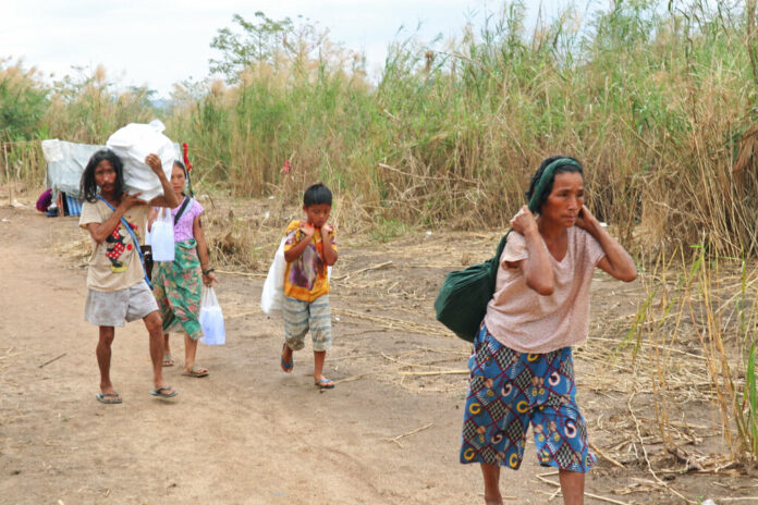 Displaced people from Myanmar carry donated lunch boxes to their tents along the Thai side of the Moei River in Mae Sot, Thailand on Feb. 5, 2022. Photo: AP