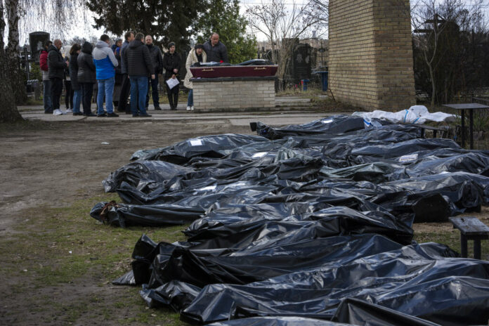 A family mourns a relative killed during the war with Russia, as dozens of black bags containing more bodies of victims are seen strewn across the graveyard in the cemetery in Bucha, in the outskirts of Kyiv, Ukraine, Monday, April 11, 2022. Photo: Rodrigo Abd / AP