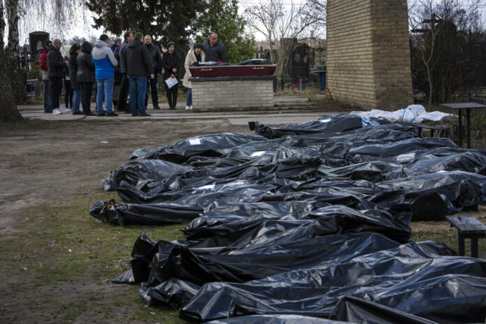 A family mourns a relative killed during the war with Russia, as dozens of black bags containing more bodies of victims are seen strewn across the graveyard in the cemetery in Bucha, in the outskirts of Kyiv, Ukraine, Monday, April 11, 2022. Photo: Rodrigo Abd / AP A family mourns a relative killed during the war with Russia, as dozens of black bags containing more bodies of victims are seen strewn across the graveyard in the cemetery in Bucha, in the outskirts of Kyiv, Ukraine, Monday, April 11, 2022. Photo: Rodrigo Abd / AP