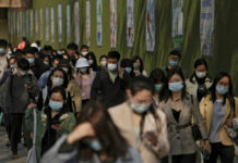 Shanghai Reports First Deaths in Current COVID-19 Outbreak People wearing face masks to help protect from the coronavirus walk by a wall displaying propaganda posters as they head to work at the Central Business District during the morning rush hour, Monday, April 18, 2022, in Beijing. Photo: Andy Wong / AP