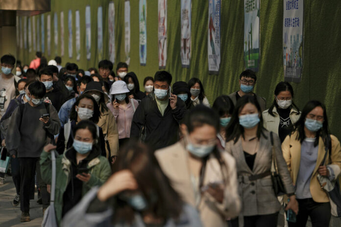 People wearing face masks to help protect from the coronavirus walk by a wall displaying propaganda posters as they head to work at the Central Business District during the morning rush hour, Monday, April 18, 2022, in Beijing. Photo: Andy Wong / AP People wearing face masks to help protect from the coronavirus walk by a wall displaying propaganda posters as they head to work at the Central Business District during the morning rush hour, Monday, April 18, 2022, in Beijing. Photo: Andy Wong / AP