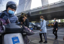 Shanghai Allows 4 Million Out of Homes as Virus Rules Ease Commuters wearing face masks walk across an intersection in the central business district in Beijing, Tuesday, April 19, 2022. Photo: Mark Schiefelbein / AP