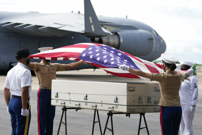 U.S. military drape a national flag over the possible remains of a WWII U.S. airman found in northern Thailand, during a repatriation ceremony Wednesday, May 18, 2022, at the U-Tapao Air Base in Rayong province, eastern Thailand. Photo: Sakchai Lalit / AP