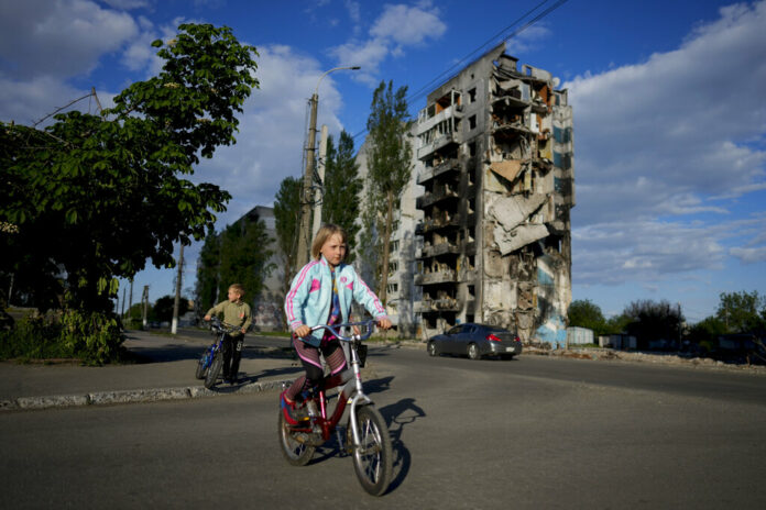 A girl rides a bicycle in front of houses ruined by shelling in Borodyanka, Ukraine, Tuesday, May 24, 2022. Photo: Natacha Pisarenko / AP