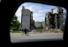 Russia Takes Steps To Bolster Army, Tighten Grip on Ukraine A man rides a bicycle in front of a building ruined by shelling in Borodyanka, on the outskirts of Kyiv, Ukraine, Wednesday, May 25, 2022. Photo: Natacha Pisarenko / AP