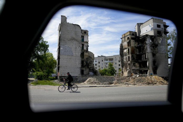 A man rides a bicycle in front of a building ruined by shelling in Borodyanka, on the outskirts of Kyiv, Ukraine, Wednesday, May 25, 2022. Photo: Natacha Pisarenko / AP