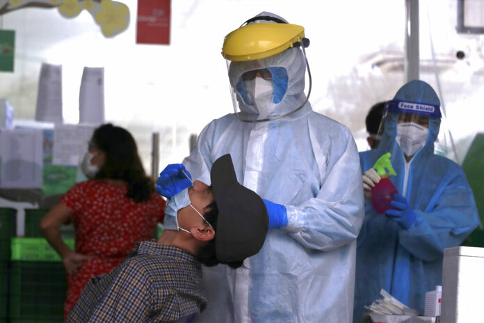 FILE - A health worker takes sample from a man for COVID-19 test in Hanoi, Vietnam on Friday, Jan. 6, 2022. Photo: Hau Dinh / AP File