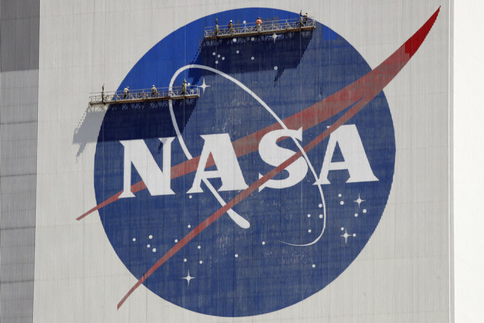 FILE - Workers on scaffolding repaint the NASA logo near the top of the Vehicle Assembly Building at the Kennedy Space Center in Cape Canaveral, Fla., Wednesday, May 20, 2020. Photo: John Raoux / AP File