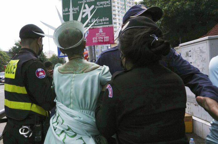 Cambodian-American lawyer Theary Seng, center, dressed in the Lady Liberty, is escorted by local police officers outside Phnom Penh Municipal Court in Phnom Penh, Cambodia, Tuesday, June 14, 2022. Photo: Heng Sinith / AP