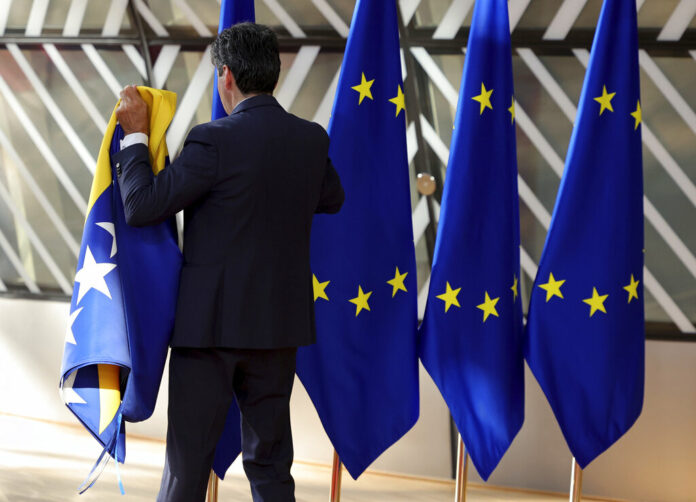 A member of protocol sets out EU and other flags prior to arrivals for an EU summit in Brussels, Thursday, June 23, 2022. Photo: Olivier Matthys / AP