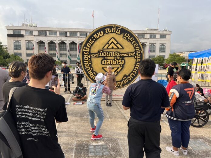 A woman poses with a replica of the 1932 Revolution plaque during a rally marking the 90th anniversary of the 1932 coup at Lan Khon Mueang Town Square on June 24, 2022.