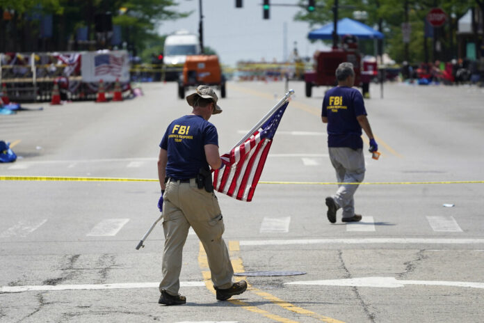 A member of the FBI's evidence response team removes an American flag one day after a mass shooting in downtown Highland Park, Ill., Tuesday, July 5, 2022. Photo: Charles Rex Arbogast / AP