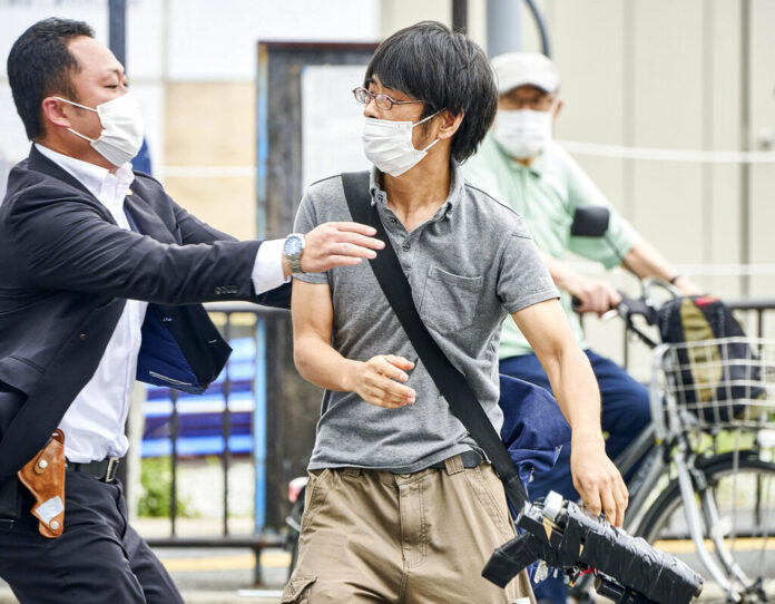 FILE - Tetsuya Yamagami, center, holding a weapon, is detained near the site of gunshots in Nara, western Japan, Friday, July 8, 2022. The 40-centimeter-long (16-inch) firearm that was used to kill former Prime Minister Shinzo Abe on Friday as he campaigned for his ruling party in Nara, western Japan, looked crude, more like a propellant made of pipes taped together and filled with explosives. Photo: Nara Shimbun / Kyodo News via AP File