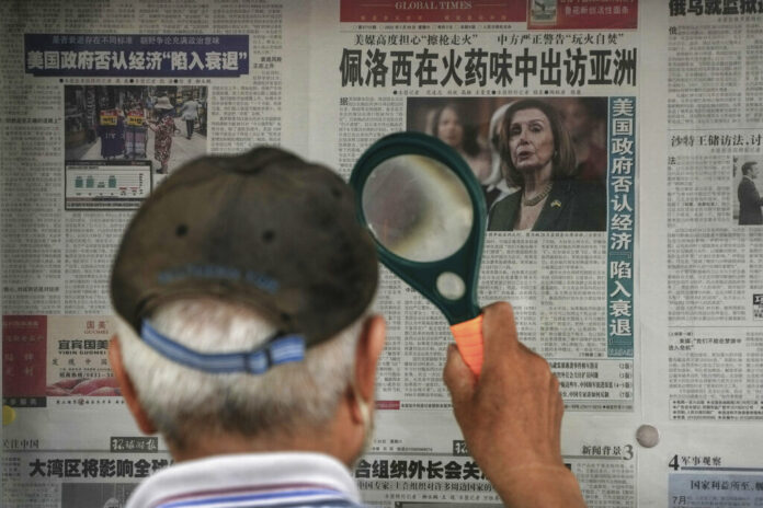 A man uses a magnifying glass to read a newspaper headline reporting on U.S. House Speaker Nancy Pelosi's Asia visit, at a stand in Beijing, Sunday, July 31, 2022. Photo: Andy Wong / AP