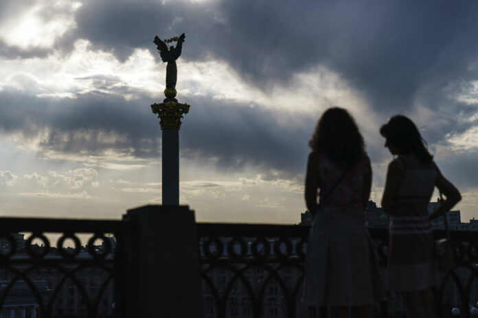 The sun sets behind the Independence Monument overlooking Maidan Square on the country's National Flag Day, Tuesday, Aug. 23, 2022, in Kyiv, Ukraine. Photo: David Goldman / AP