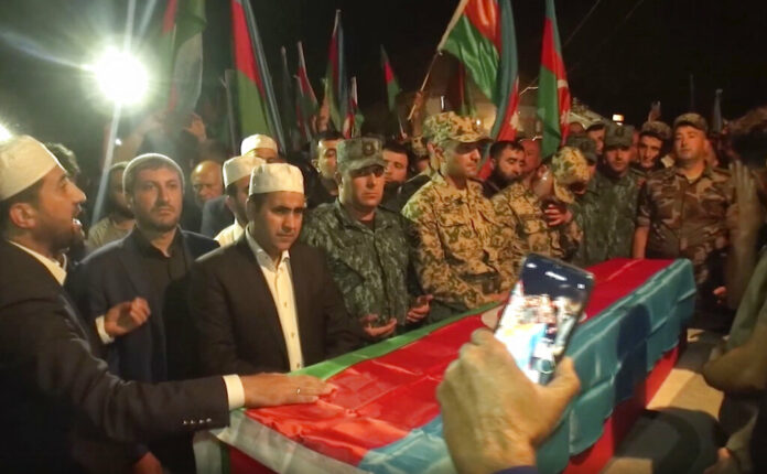 In this image taken from video, people stand around a coffin of Azeri serviceman Elshan Babazade killed at Azerbaijani-Armenian border, during his funeral in Mykhlygovag, Azerbaijan, Tuesday, Sept. 13, 2022. Photo: AP