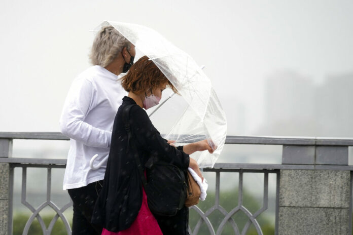 People share an umbrella against strong wind and rain Tuesday, Sept. 20, 2022, in Kawasaki, near Tokyo. Photo: Eugene Hoshiko / AP