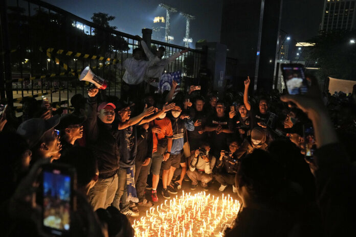 Indonesian soccer fans chant slogans during a candle light vigil for the victims of Saturday's soccer riots, in Jakarta, Indonesia, Sunday, Oct. 2, 2022. Photo: Dita Alangkara / AP
