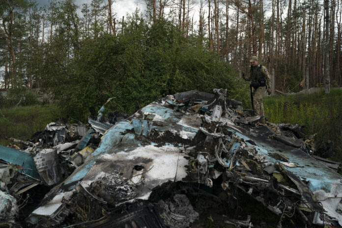 A Ukrainian serviceman walks over the remains of Russian aircraft SU-34 in an area at the recaptured town of Lyman, Ukraine, Wednesday, Oct. 5, 2022. Photo: Leo Correa / AP