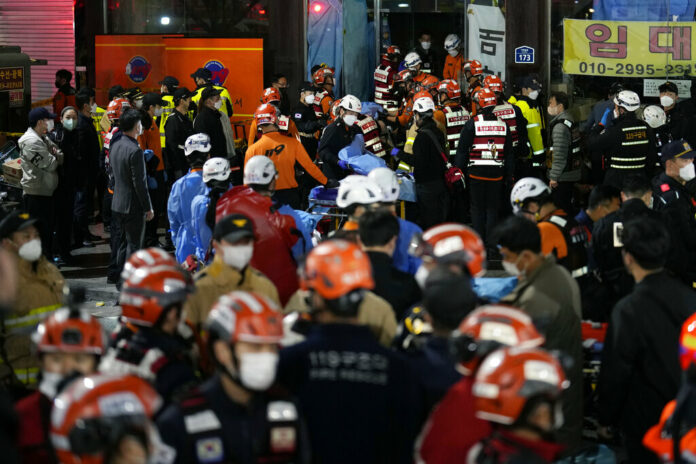 Rescue workers try to carry victims on the street near the scene, in Seoul, South Korea, Sunday, Oct. 30, 2022. Photo: Lee Jin-man / AP