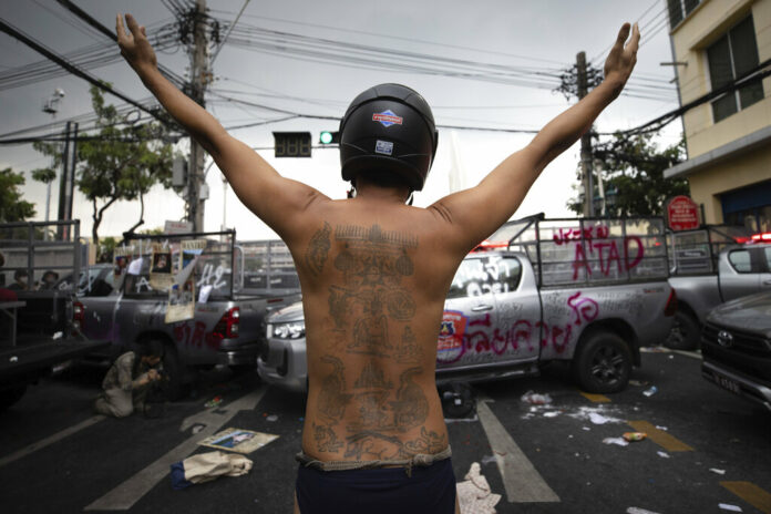 A protester raises his arms behind vandalized police vehicles during a confrontation with police as they try to march to the Asia-Pacific Economic Cooperation APEC summit venue, Friday, Nov. 18, 2022, in Bangkok, Thailand. Photo: Wason Wanichakorn / AP