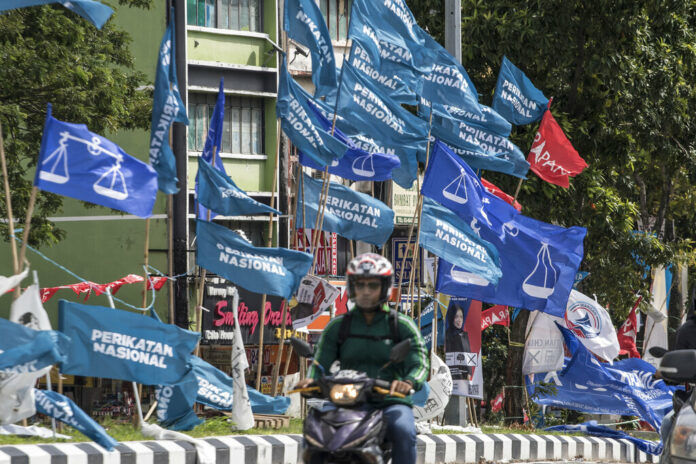 Motorcycles passing by campaign flags of Malaysia's ruling National Front coalition, or Barisan Nasional (blue) and Pakatan Harapan (Alliance of Hope) coalition (red) displayed in Kuala Lumpur, Malaysia, Sunday, Nov. 20, 2022. Photo: Ahmad Yusni / AP Motorcycles passing by campaign flags of Malaysia's ruling National Front coalition, or Barisan Nasional (blue) and Pakatan Harapan (Alliance of Hope) coalition (red) displayed in Kuala Lumpur, Malaysia, Sunday, Nov. 20, 2022. Photo: Ahmad Yusni / AP
