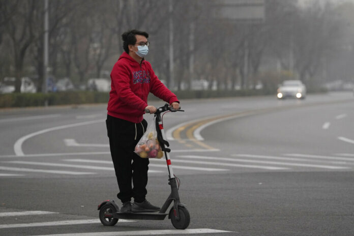 A resident rides a scooter along a quiet street in a district as restaurants are shut and residents encouraged to stay in their vicinity in Beijing, Thursday, Nov. 24, 2022. Photo: Ng Han Guan / AP