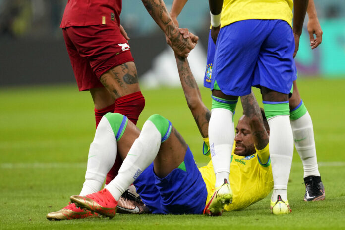 Brazil's Neymar is helped back on his feet during the World Cup group G soccer match between Brazil and Serbia, at the Lusail Stadium in Lusail, Qatar, Thursday, Nov. 24, 2022. Photo: Andre Penner / AP