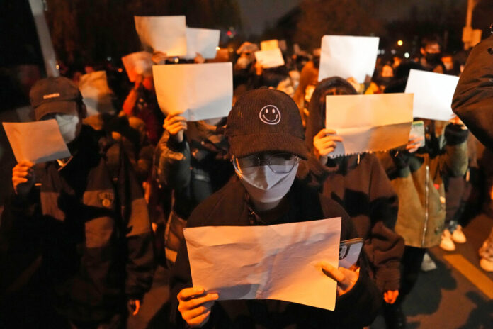 Protesters hold up blank papers and chant slogans as they march in protest in Beijing, Sunday, Nov. 27, 2022. Photo: Ng Han Guan / AP Protesters hold up blank papers and chant slogans as they march in protest in Beijing, Sunday, Nov. 27, 2022. Photo: Ng Han Guan / AP