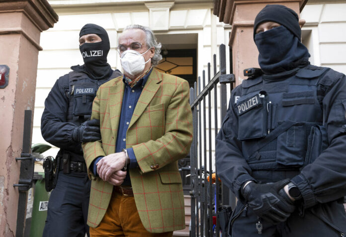 Masked police officers lead Heinrich XIII Prince Reuss, center, to a police vehicle during a raid against so-called 'Reich citizens' in Frankfurt, Germany, Wednesday, Dec. 7, 2022. Photo: Boris Roessler / dpa via AP